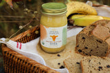 Jar of 'Spring Sunrise' brown butter ghee with bread and bananas on a wooden surface