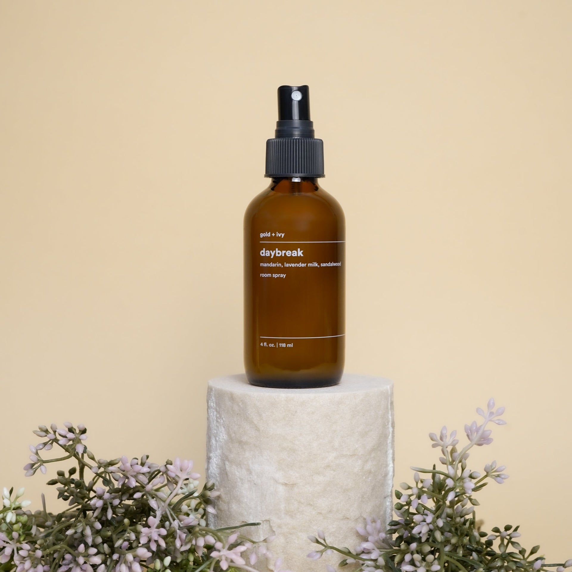 Brown spray bottle labeled 'daybreak' on a beige background with floral elements.