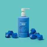 Dabble & Dollop Blueberry Gel bubbles bath product sits amongst paper-crafted blueberry boxes on a bright teal background.
