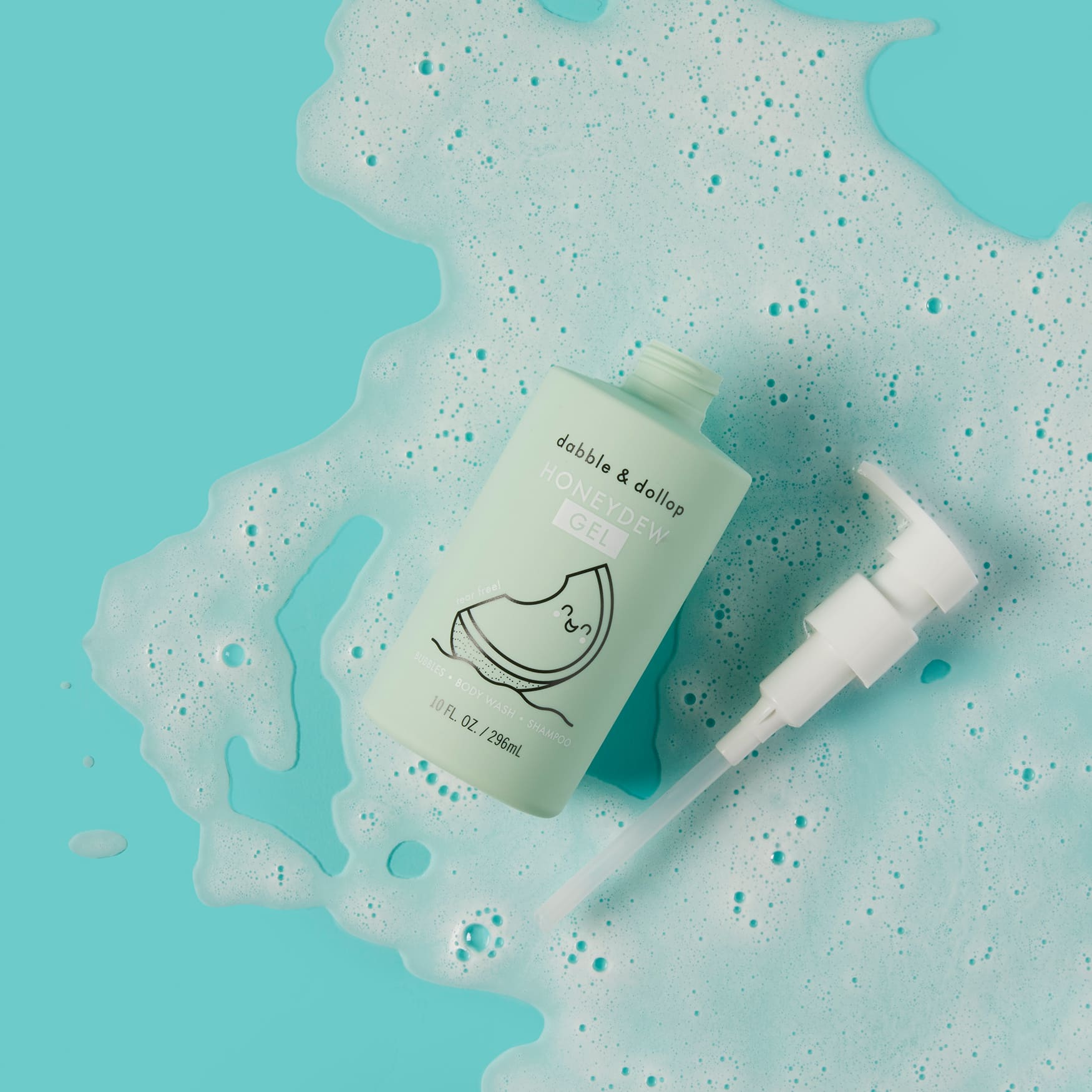 Dabble & Dollop Honeydew Gel body wash bottle sits in a pool of bubbly foam against a bright turquoise background.
