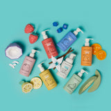Dabble & Dollop children's bath products showcase their fruity scents like strawberry, coconut, lemon, and tangerine with colorful packaging and paper fruit decorations on a bright blue background.
