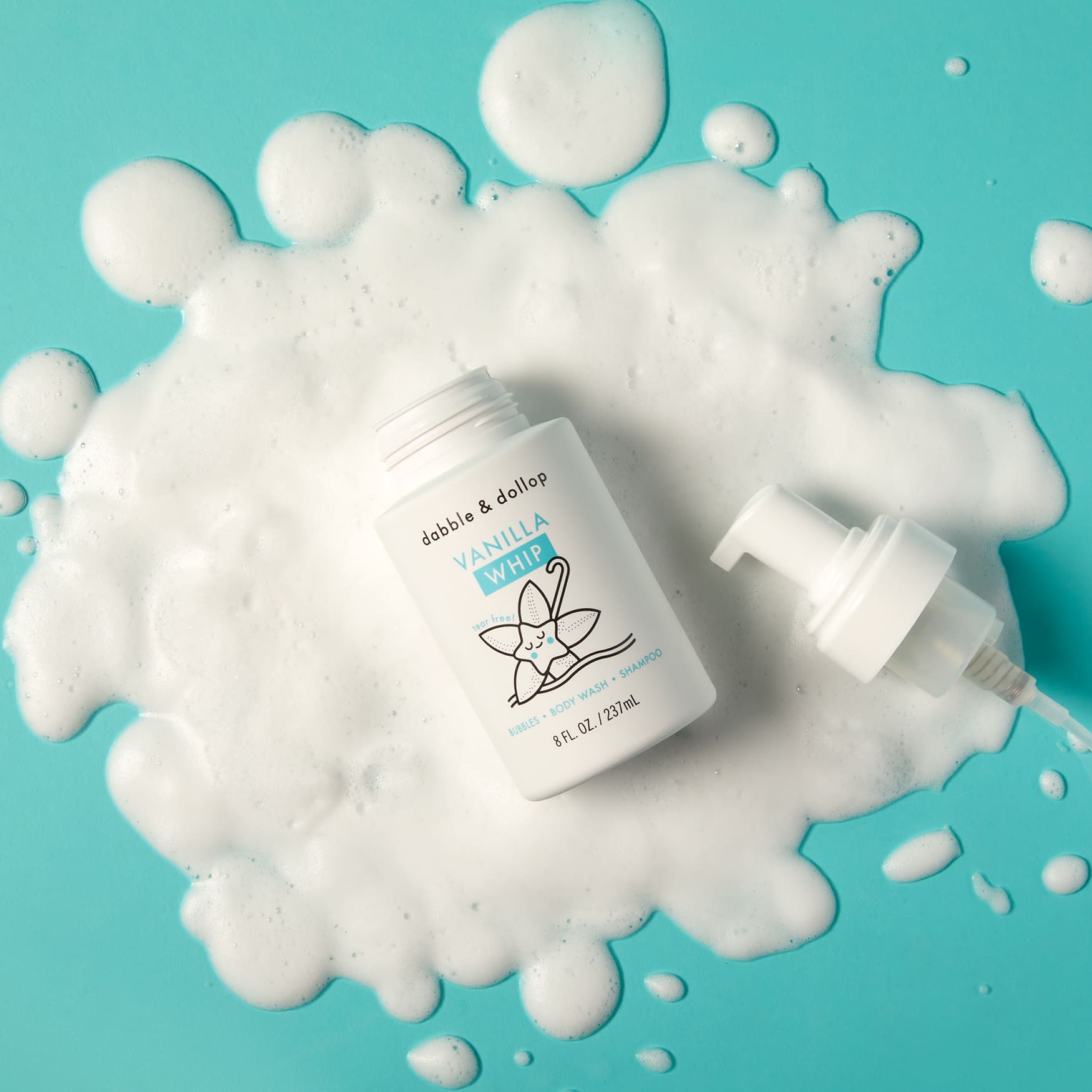 Dabble & Dollop Vanilla Whip bubbles body wash sits amidst foamy suds on a bright blue surface.
