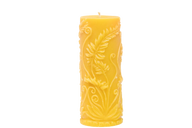 A beeswax candle shows off its intricate, floral-themed carved design.
