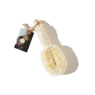 A dry brush and its tag show a woman using a similar brush on her skin for exfoliation and skincare.
