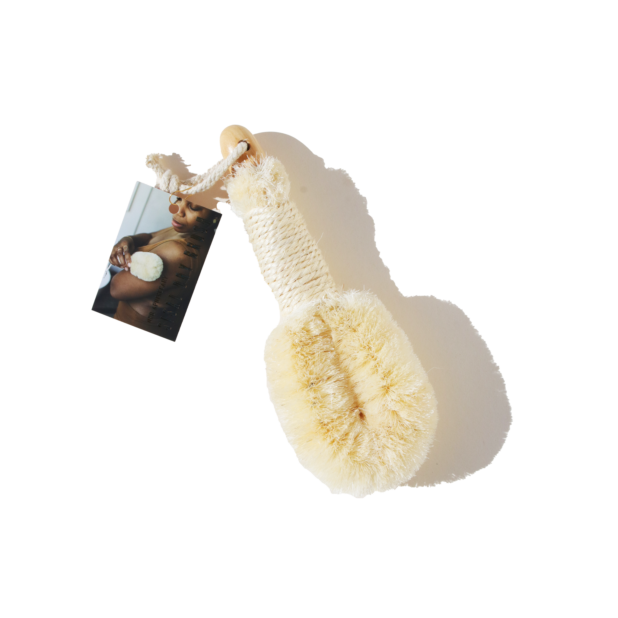 A dry brush and its tag show a woman using a similar brush on her skin for exfoliation and skincare.
