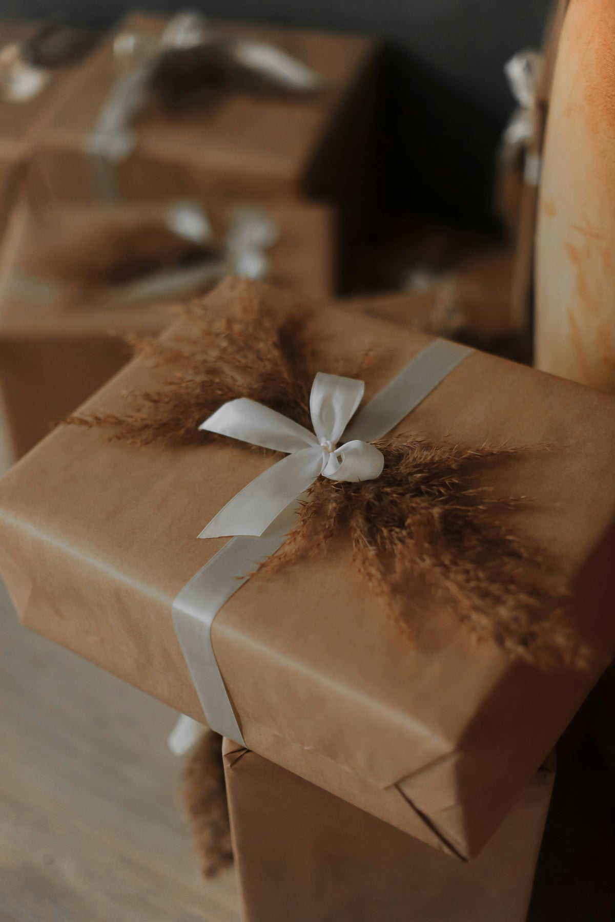 Gift wrapped in brown paper with a white ribbon on a wooden surface.