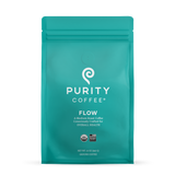 Purity Coffee Flow medium roast, packaged in a teal bag, offers consciously crafted organic ground coffee.
