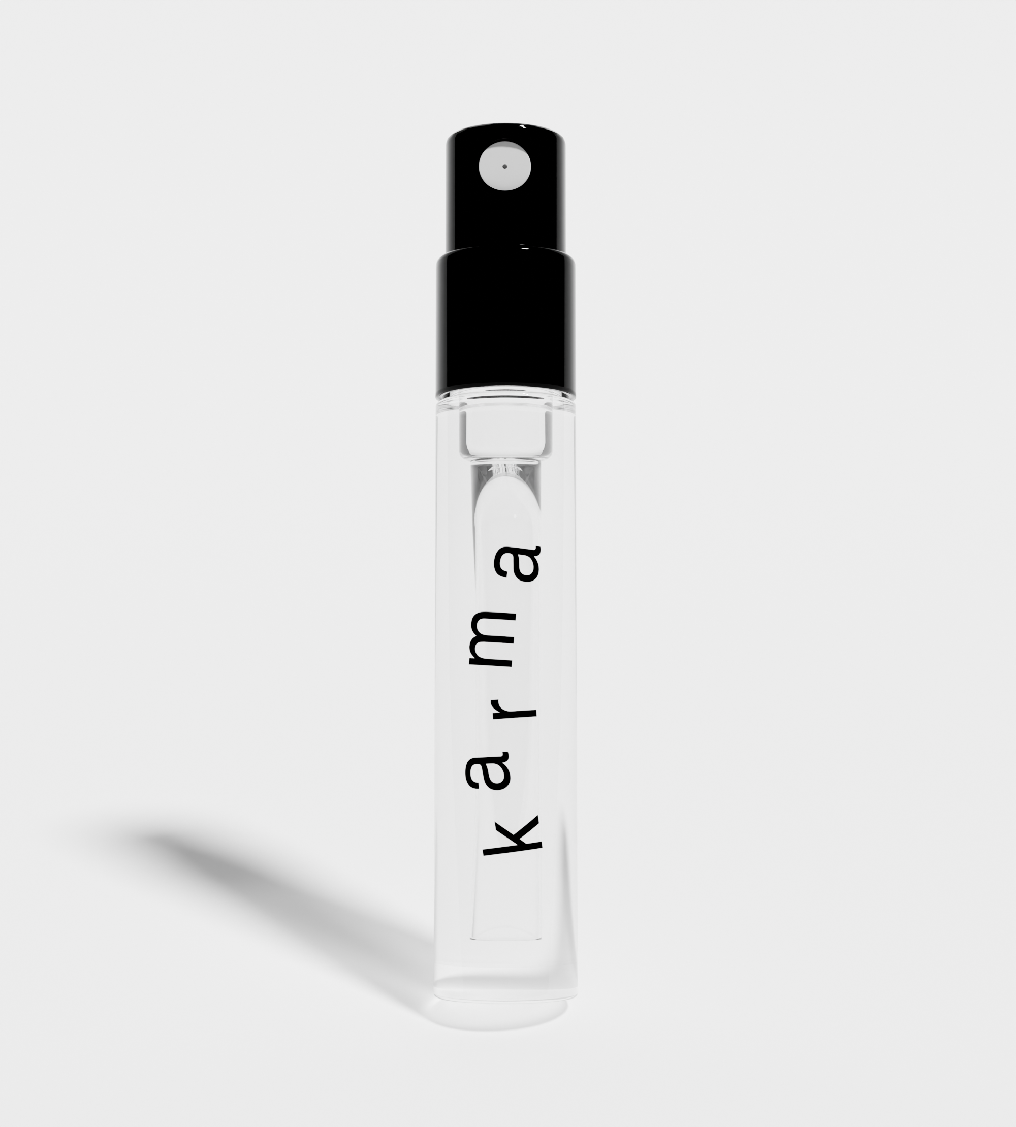 Close-up showcases a travel-size Karma perfume atomizer with a black top and clear glass filled with fragrance.

