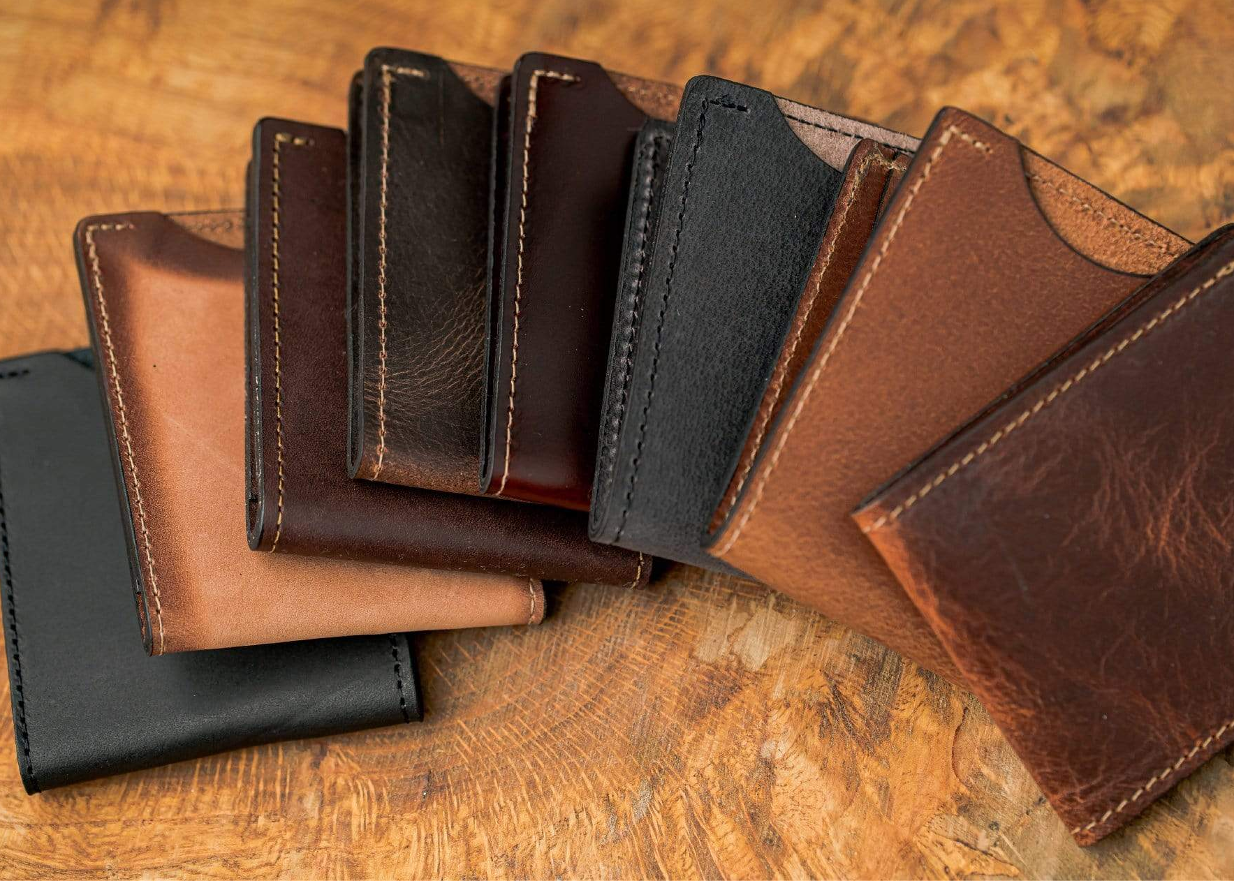 Collection of leather wallets in various colors on a wooden surface with text about color options.