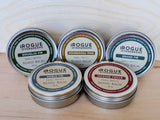 Rogue Evergreens displays their small-batch beard balm collection featuring Douglas Fir, Ponderosa Pine, Grand Fir, Noble Fir, and Incense Cedar scents.
