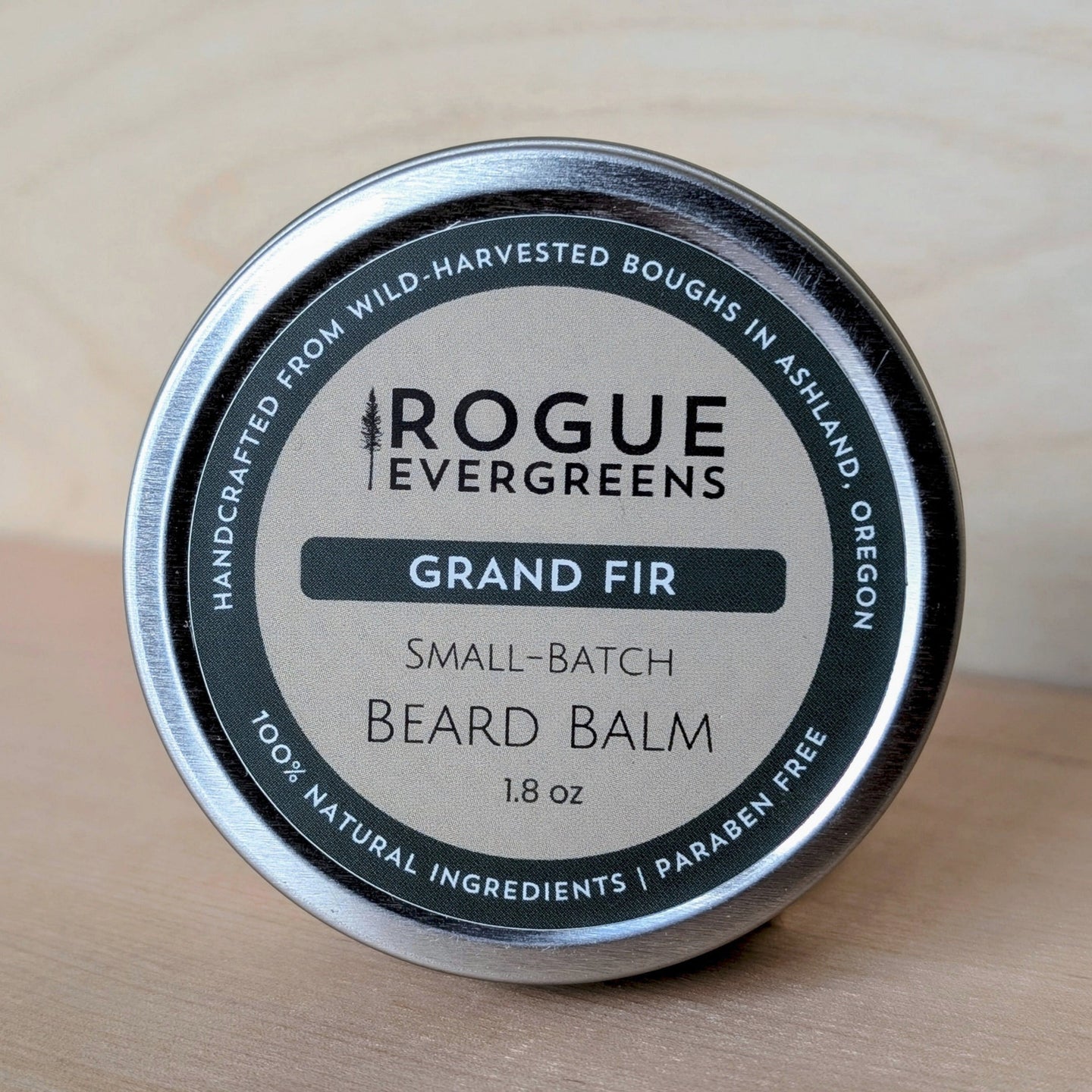 Showcases a tin of Rogue Evergreens Grand Fir beard balm made with wild-harvested ingredients in Ashland, Oregon.
