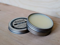 Two tins of Rogue Evergreens Grand Fir beard balm sit on a wooden surface.
