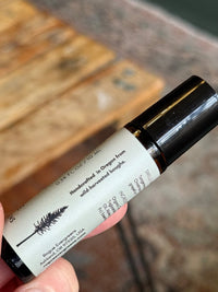 Someone holds a Rogue Evergreens aromatherapy rollerball made with wild-harvested Oregon boughs.
