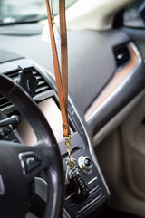 Keys hang from an Urban Southern leather lanyard inside a car.
