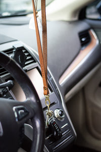 Keys hang from an Urban Southern leather lanyard inside a car.
