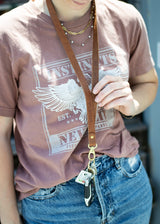Woman holds a leather lanyard with keys attached, showcasing stylish everyday carry accessories.

