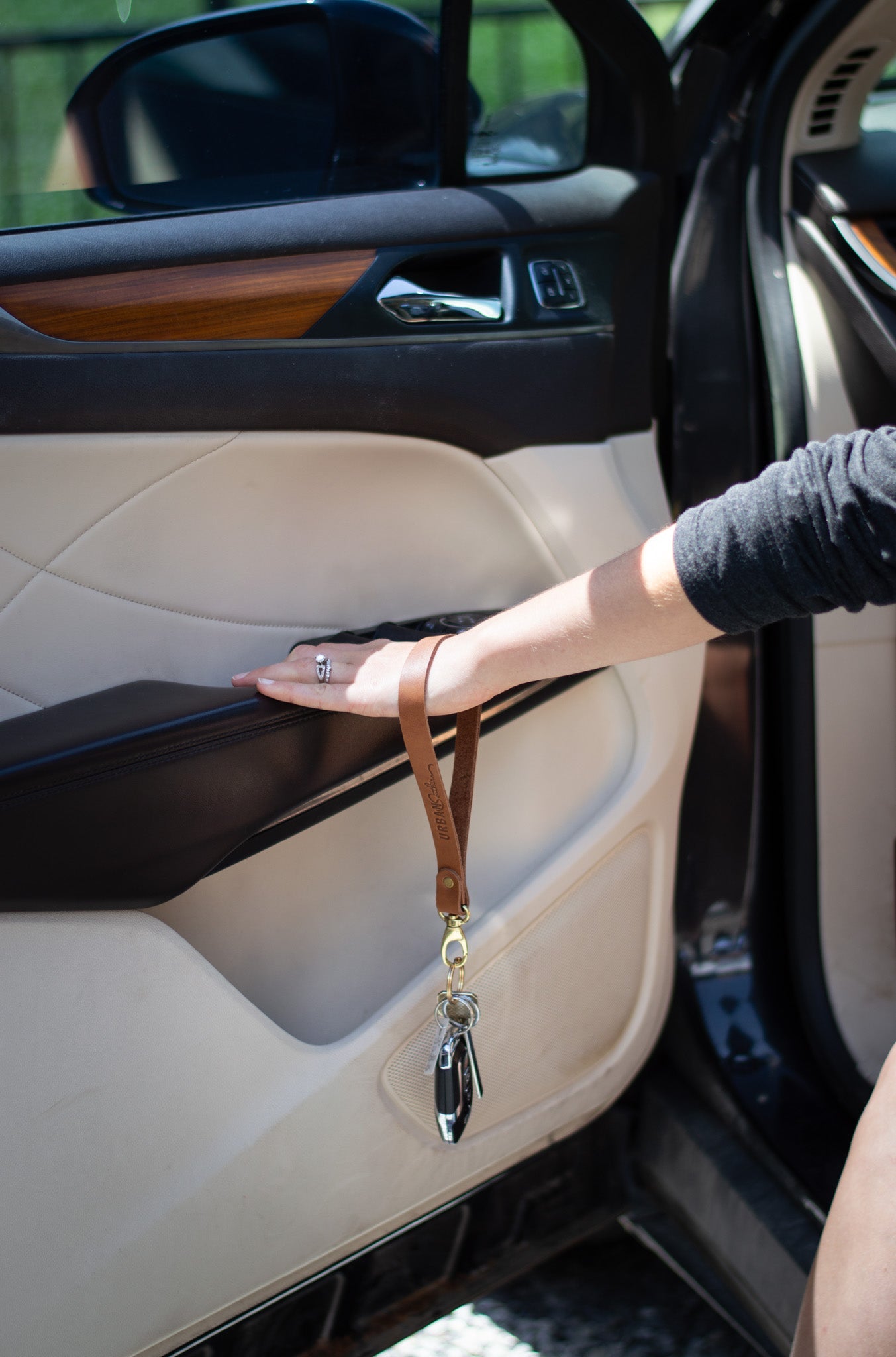 A woman holds a leather key lanyard with car keys inside a luxury vehicle.
