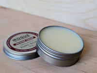 Close-up showcases Rogue Evergreen's Incense Cedar small-batch beard balm in an open tin on a wooden surface.
