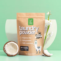 Green Llama's fragrance-free laundry powder, displayed with a coconut and white flowers, offers a biodegradable and health-conscious cleaning solution.
