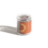A glass jar filled with fragrant lavender bath salts sits on a white surface.

