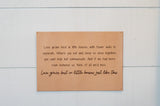 Wooden wall displays an inspirational quote about love growing in small homes, emphasizing family and togetherness.
