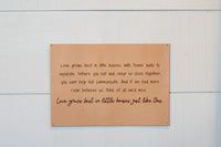 Wooden wall displays an inspirational quote about love growing in small homes, emphasizing family and togetherness.
