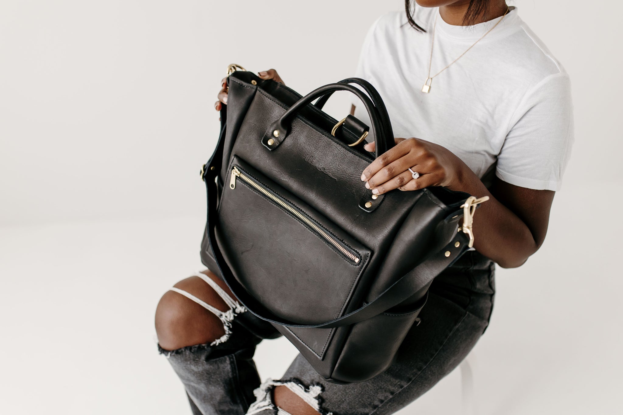Woman holds a luxury black leather tote bag, showcasing its craftsmanship and versatile design.

