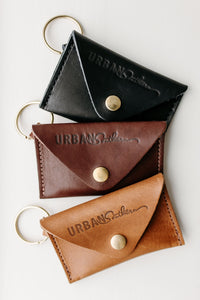 Stack of leather coin purses with key rings displays "Urban Southern" logo.
