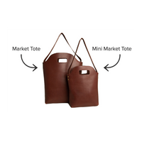 Two brown leather market totes, one full-sized and one mini, sit side-by-side against a white background.
