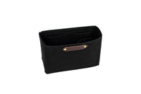 Displaying a black felt purse organizer with interior pockets and a leather logo patch against a white background.
