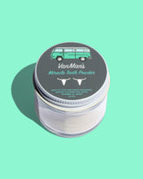 VanMan's Miracle Tooth Powder sits in a clear jar with a lid featuring a VW bus illustration and natural ingredients like bone-derived hydroxyapatite for healthy oral care.
