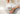 A person holding a glass jar of Slow North of the Sea Bath Salts, with their hand reaching in to scoop the white bath salts. The person is wearing a light blue sweatshirt and a white towel, set against a soft, warm, blurred background.