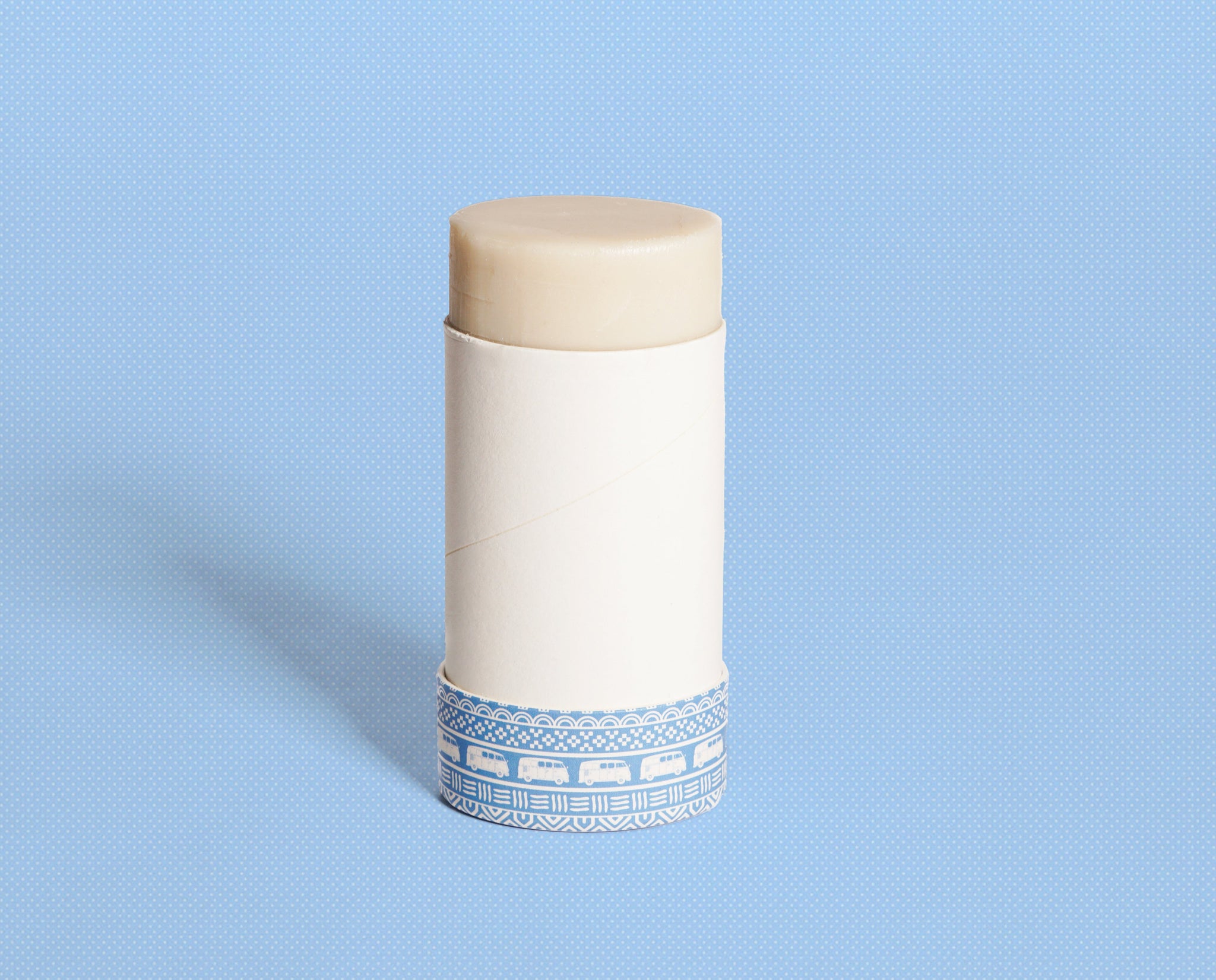 Showcasing a plastic-free deodorant balm in a paper tube, decorated with blue vans on a polka-dot background.
