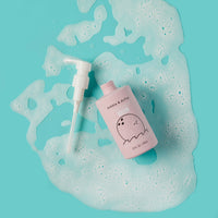 Dabble & Dollop Coconut Gel body wash rests amid foamy bubbles on a bright blue surface.
