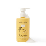 Dabble & Dollop Lemon Gel body wash bottle spills foam on a white surface.
