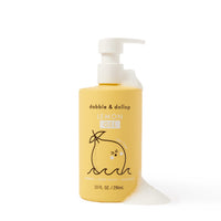 Dabble & Dollop Lemon Gel body wash bottle spills foam on a white surface.
