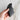 Hand holds a dark green jade gua sha tool against a marble background.
