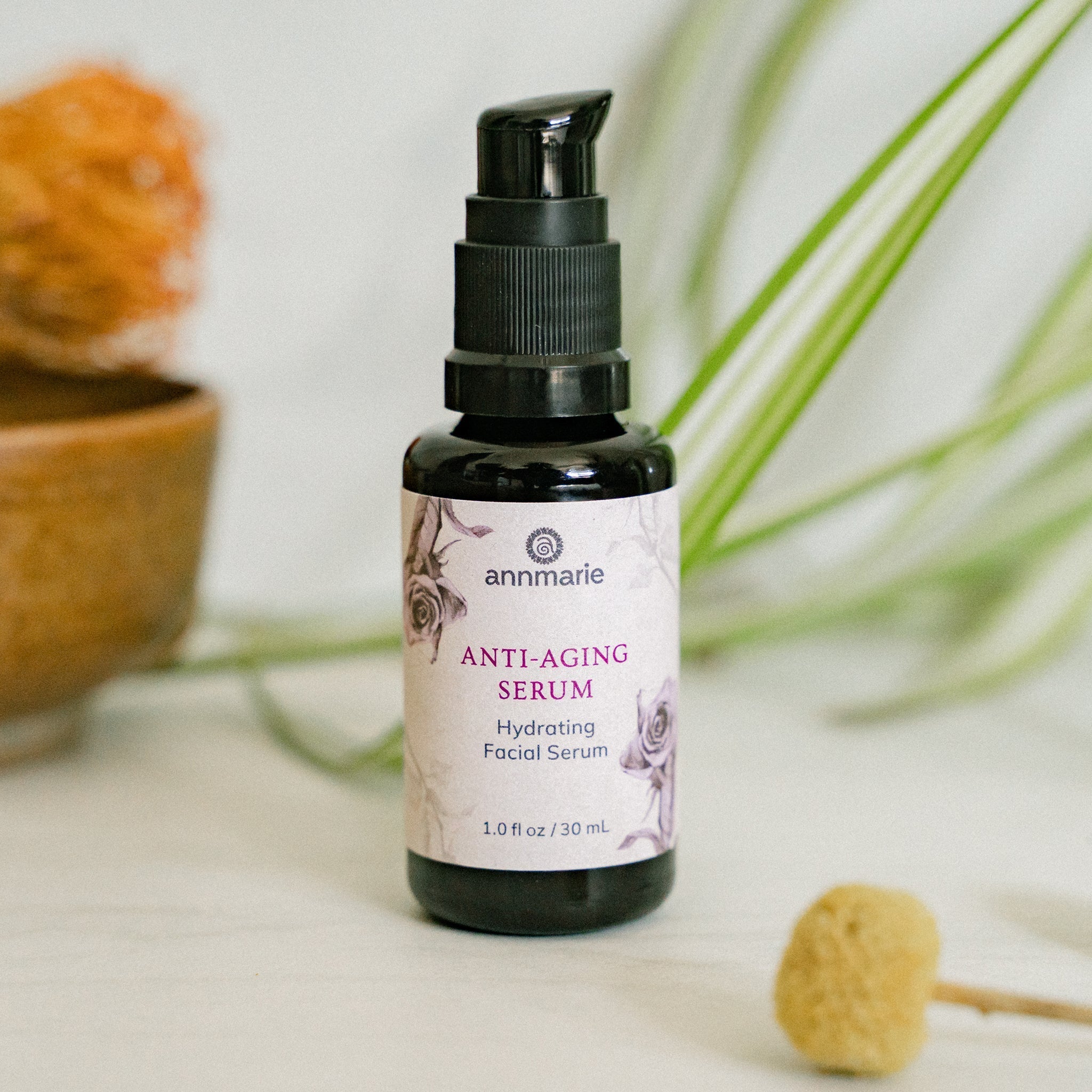 Annmarie Anti-Aging Serum bottle sits among decorative plants.
