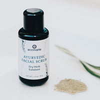 Annmarie Ayurvedic facial scrub bottle sits beside a pile of its dry herb exfoliant powder.
