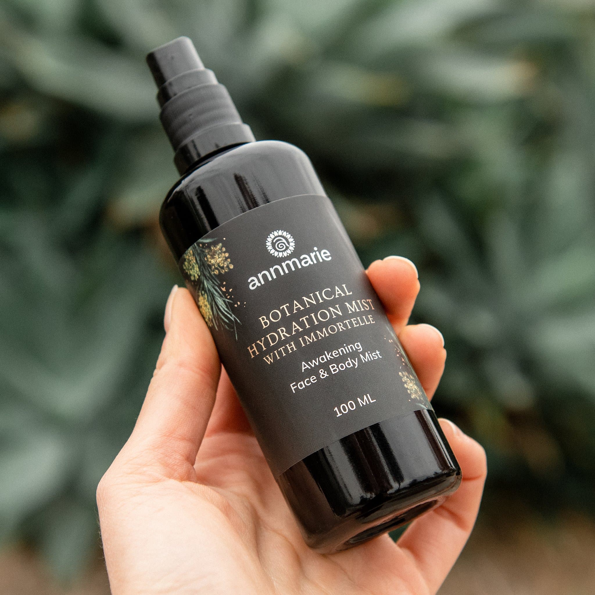 A hand holds a bottle of Annmarie Botanical Hydration Mist for face and body.

