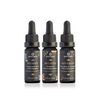 Three Annmarie skincare serum bottles, labeled Hydrate, Brighten, and Revitalize, stand side-by-side on a white surface.
