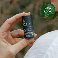 A woman showcases Annmarie Antioxidant Lip Balm, highlighting its new look and natural ingredients like cocoa butter.

