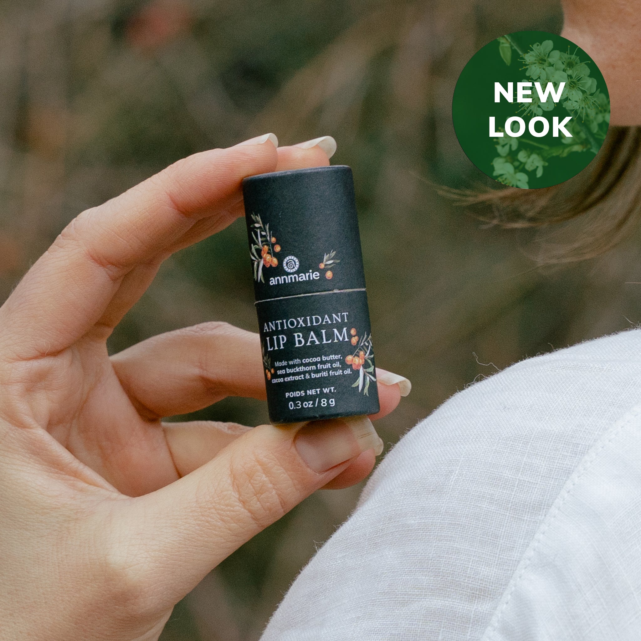 A woman showcases Annmarie Antioxidant Lip Balm, highlighting its new look and natural ingredients like cocoa butter.
