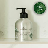 Annmarie's new rosemary peppermint body wash in a silver bottle sits on a marble shelf.
