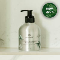 Annmarie's new rosemary peppermint body wash in a silver bottle sits on a marble shelf.
