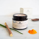 Annmarie Illuminating Pearl Mask sits alongside turmeric powder, aloe vera, and a miswak stick, showcasing natural skincare ingredients.
