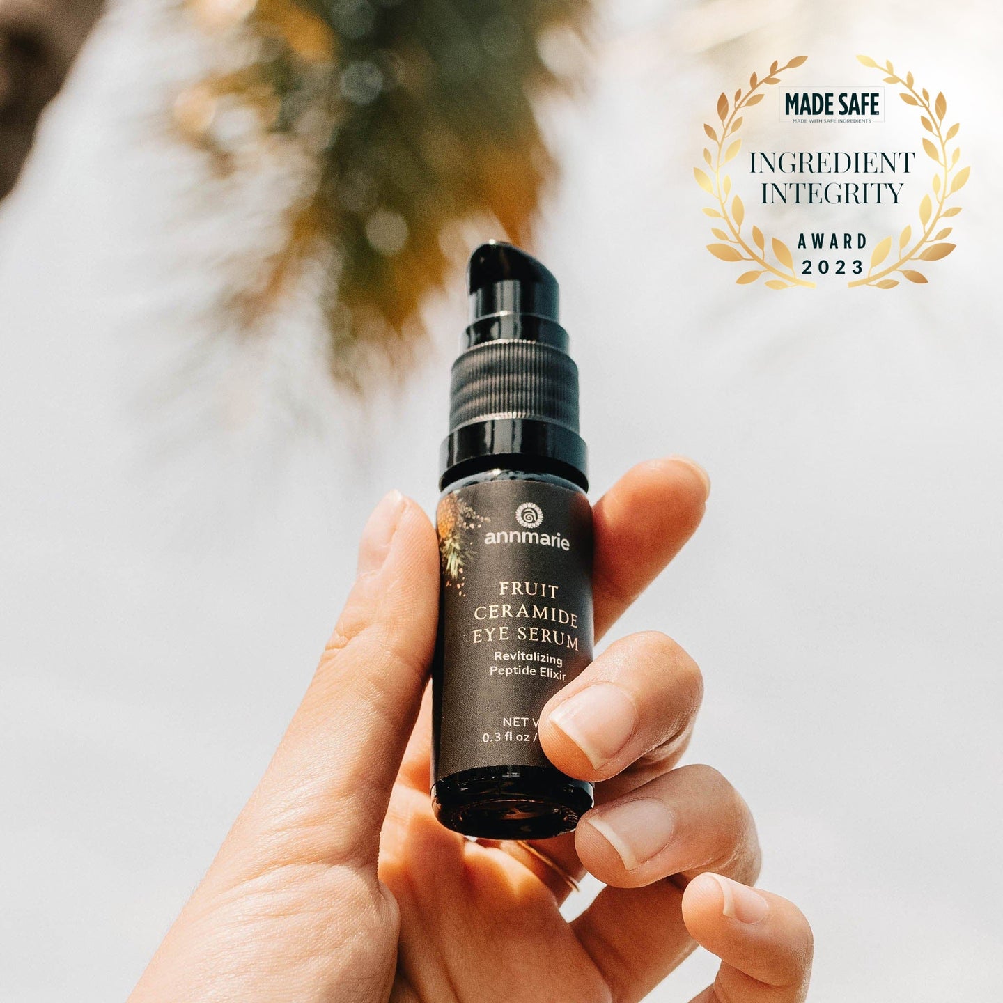 Hand holds Annmarie Fruit Ceramide Eye Serum, showcasing its "Made Safe" Ingredient Integrity Award for 2023.
