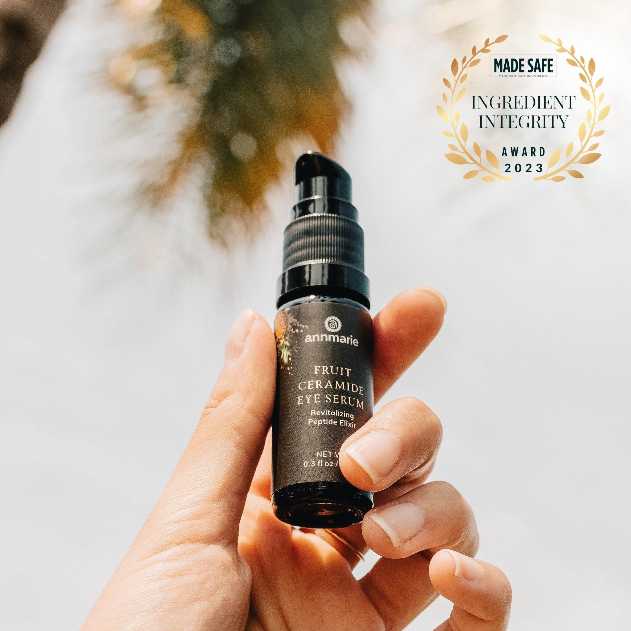 Hand holds Annmarie Fruit Ceramide Eye Serum, showcasing its "Made Safe" Ingredient Integrity Award for 2023.
