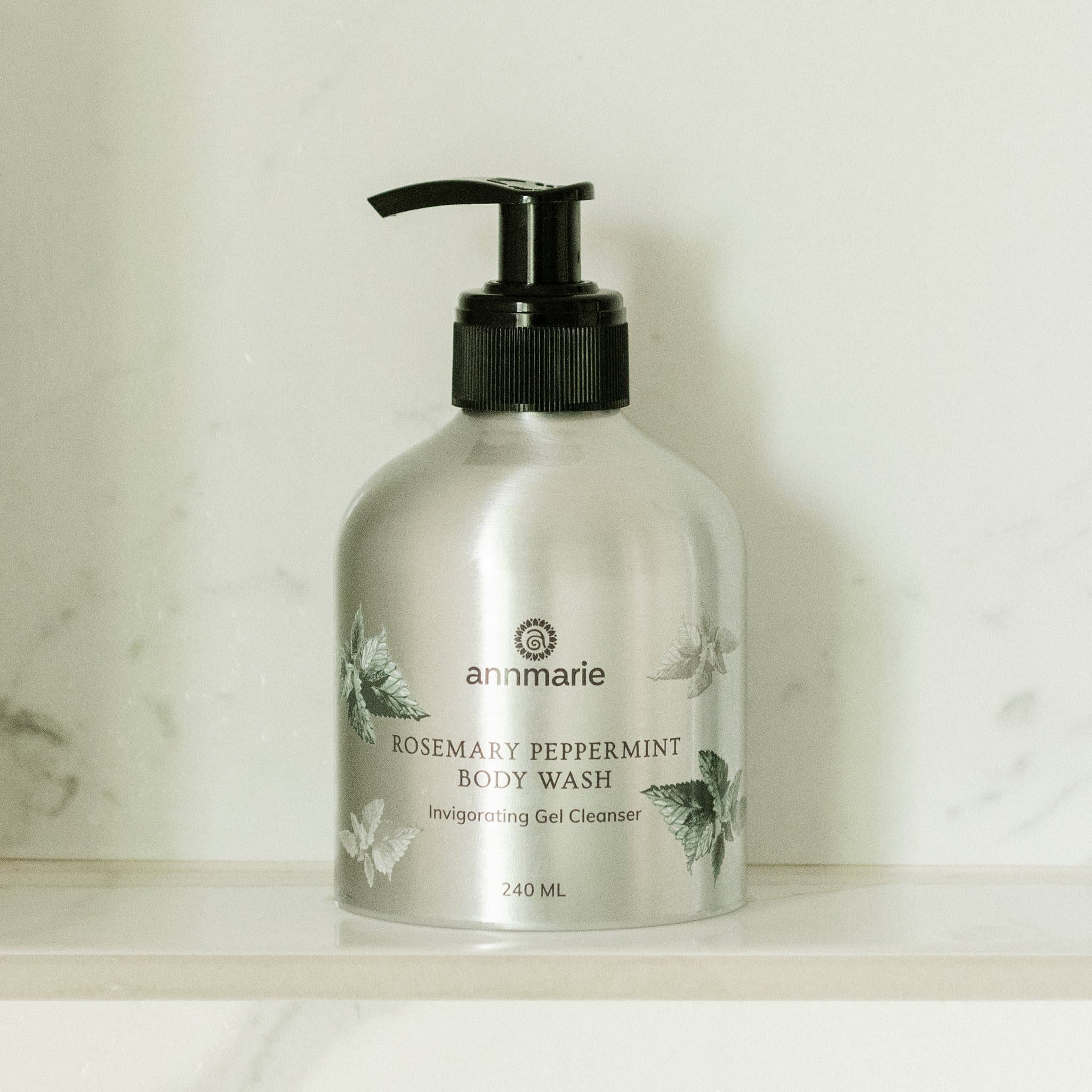 Annmarie Rosemary Peppermint Body Wash sits on a marble shelf, showcasing its invigorating gel cleanser.
