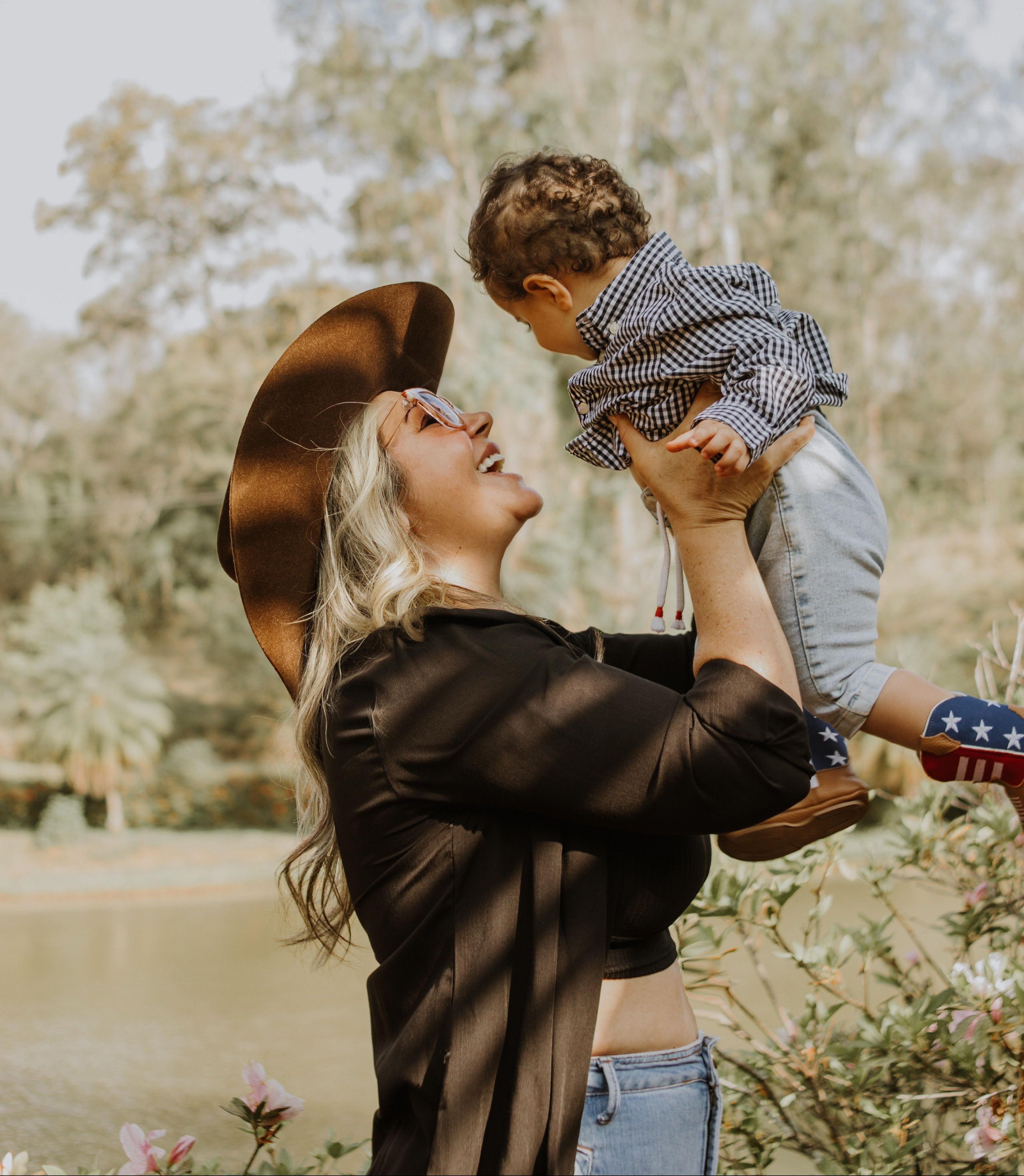 Mom in cowboy hat holding toddler with american-flag print cowboy boots